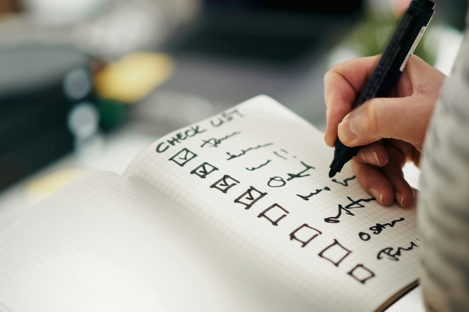 يد تحمل قلماً وتضع علامات صح على قائمة مهام مطبوعة